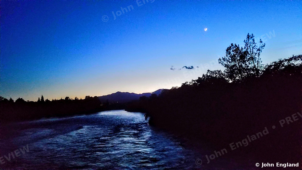 Blue Hour River with Venus – Blue-hour river with Venus and the moon above the tree line.