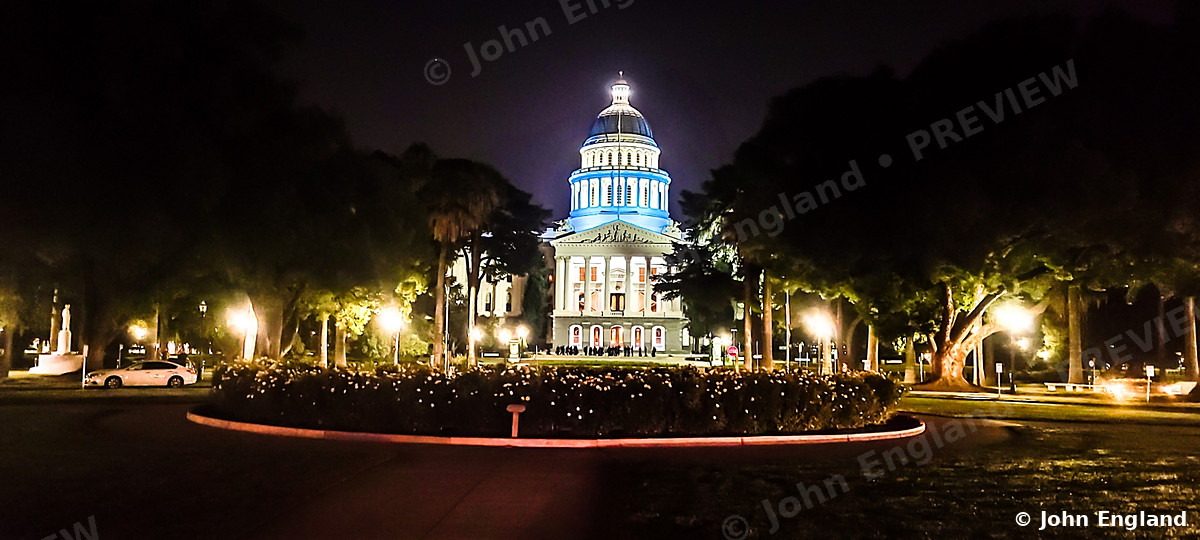 Domed Capitol Building at Night – Lit domed government building at night framed by trees.