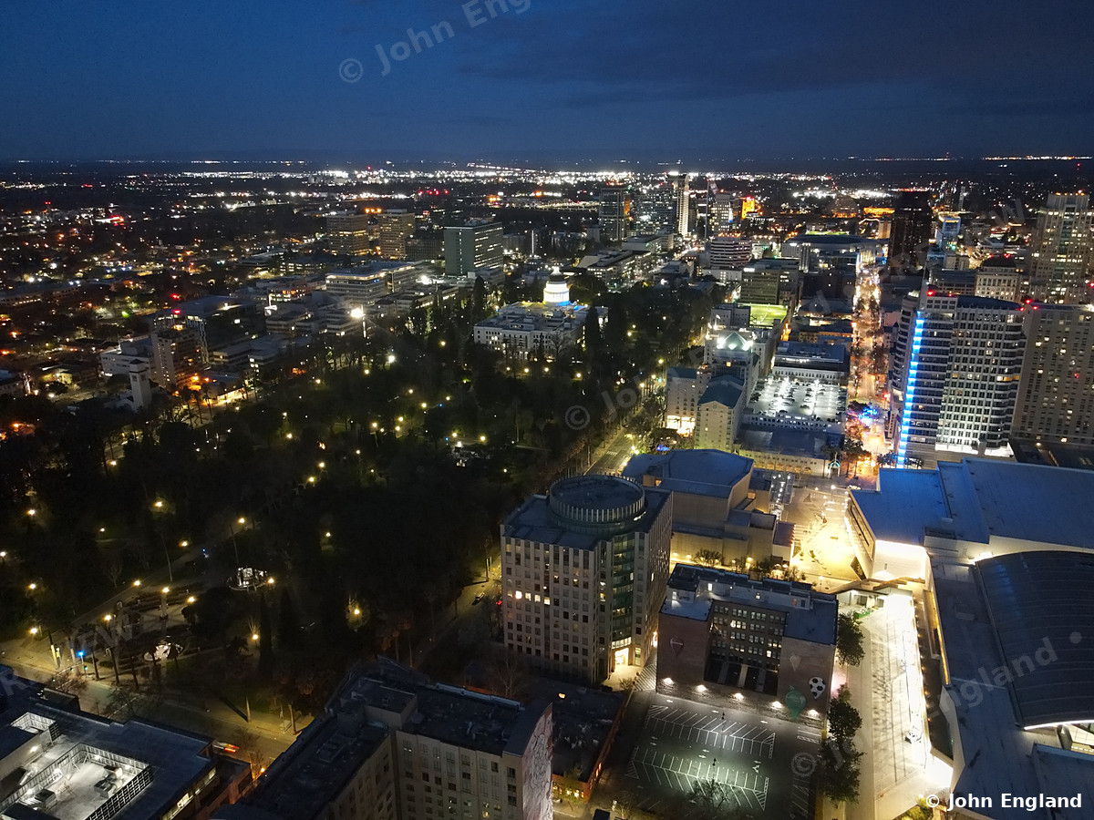 Downtown Lights from Above – Aerial night view of downtown with blue-lit tower and light-lined streets.