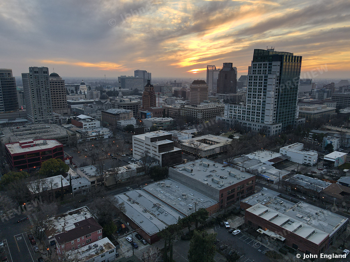 Golden Clouds Downtown – Aerial of downtown towers under golden-lit clouds.