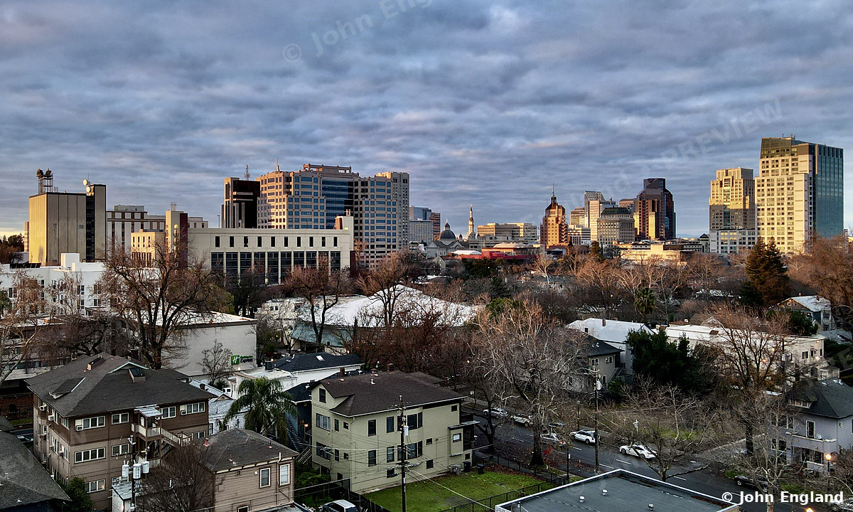 Sacramento Skyline Over Midtown Rooftops – Aerial view over Midtown rooftops toward the downtown Sacramento skyline, CA. Dec 2021. John England.