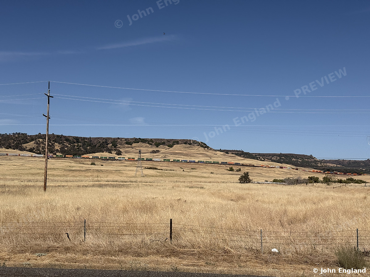 Golden Grass Below the Mesa, Butte County – Golden summer grassland and a passing freight train below a flat-topped mesa north of Oroville, Butte County. Aug 26, 2026. John England.