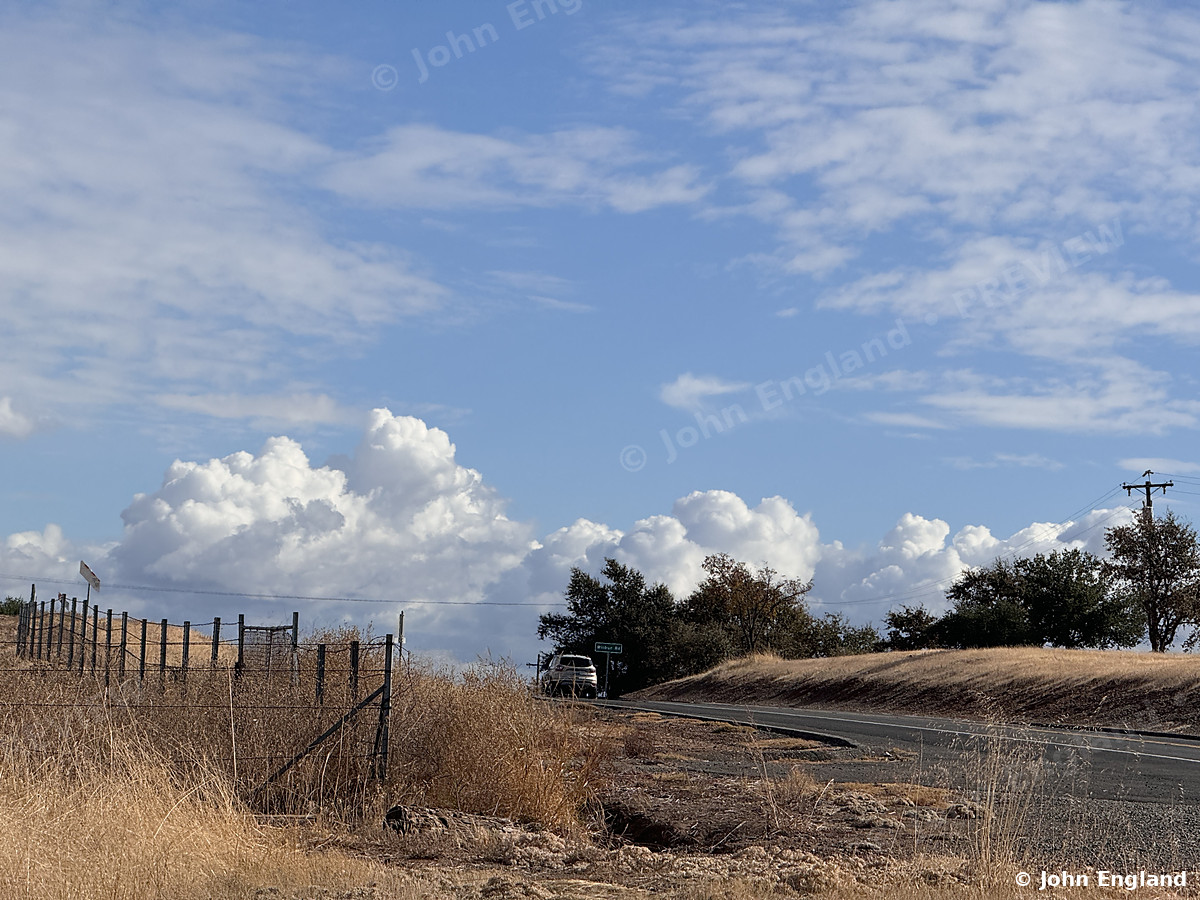 Summer Clouds Over the Foothills – Towering cumulus clouds over dry foothills and a country road. Oct 28, 2024. John England.