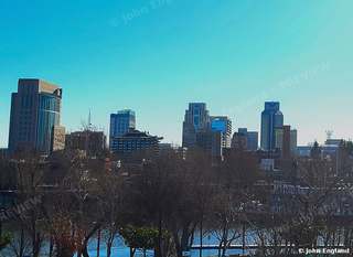Clear Sky Skyline – Downtown towers above bare winter trees under clear blue sky.