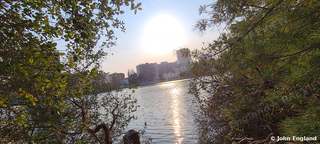 Riverside Sunburst – Sun over a river with distant city towers, Aug 28, 2020.