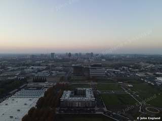 City at Dusk from Above – Drone view across the city toward a downtown skyline at dusk. John England.