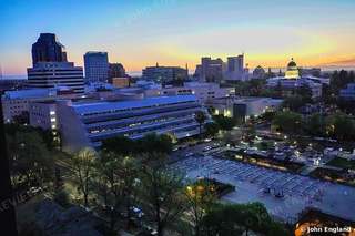 City Twilight from Above – A city at twilight from a high window, with a lit dome on the skyline. John England.